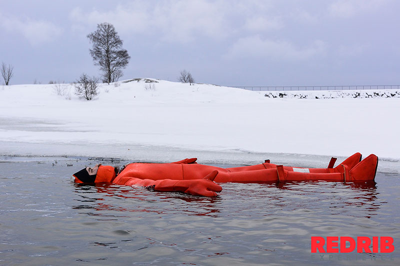 Person wearing a survival suit floating in the icy water